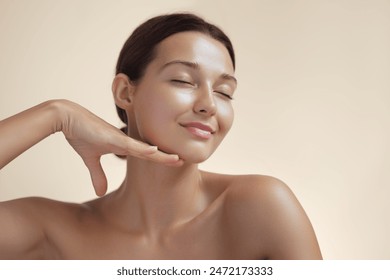 High-quality photo of skincare and cosmetics concept with copy space for text. Natural beauty woman woman with radiant, glowing skin closes her eyes and gently touches her face with her hand, creating - Powered by Shutterstock