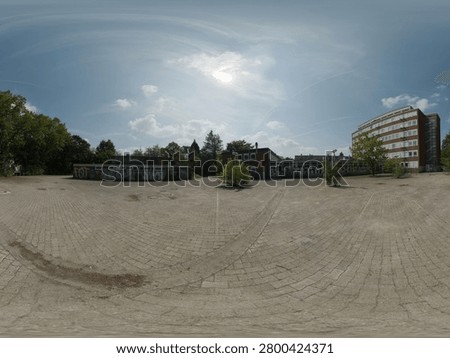 High-resolution 360-degree panoramic view of an open urban courtyard featuring a large paved plaza, low-rise buildings with graffiti-covered walls, modern office architecture, and surrounding trees under a bright blue sky. The scene highlights a mix of contemporary urban development, public space, street art, and industrial-style city infrastructure. Ideal for cityscape, urban planning, architecture, real estate, virtual reality, and HDRI environment projects.