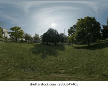 High-resolution 360-degree panoramic view of a spacious urban park featuring expansive green lawns, mature trees, walking paths, and a distant view of the iconic Eiffel Tower rising above the treetops. Captured on a bright sunny day with dramatic cloud formations, this peaceful city park combines natural beauty with a famous landmark, making it ideal for virtual reality environments, HDRI backgrounds, travel content, tourism promotions, and landscape visualization projects.