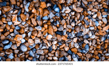 A high-resolution close-up of a gritty texture formed by a mixture of gravel and various stones. This rough and grunge texture can add depth and character to your design projects.