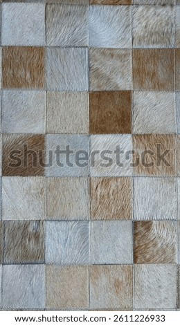 High-resolution close-up of a patchwork surface made of natural cowhide or leather squares in varying shades of beige, brown, and grey. Stitched edges and visible hair texture.