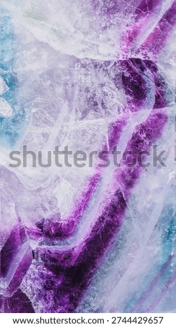 High-resolution macro image of raw purple fluorite specimen revealing stunning violet, lavender and turquoise color zones, crystalline structure and natural inclusions. Geology and crystal healing theme.