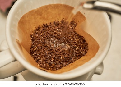         High-resolution macro photography capturing the step-by-step hand drip coffee brewing process. The sequence shows fresh roasted coffee beans inside a manual burr grinder, followed by the blooming phase in a paper filter where hot water causes the coffee grounds to release trapped carbon dioxide, creating a textured dome of bubbles. This visual narrative highlights the scientific and physical extraction process of specialty coffee.                       