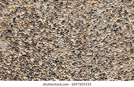 A high-resolution, overhead view of exposed aggregate concrete or pebble pavement, featuring a dense, rough texture composed of numerous small, multicolored, rounded stones
