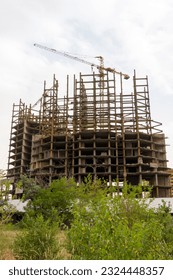 High-rise building construction using tower cranes. low angle photo of building under construction. Apartment building under construction on a cloudy day.