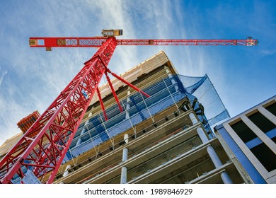 Highrise Building Site in Berlin. Looking up at the construction site of a high-rise building with red crane in the foreground.