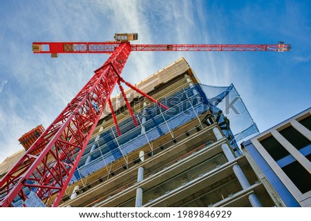 Highrise Building Site in Berlin. Looking up at the construction site of a high-rise building with red crane in the foreground.