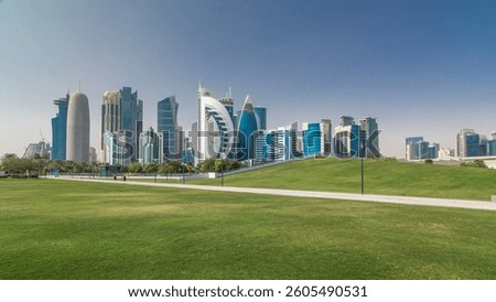 The high-rise district of Doha timelapse hyperlapse, seen from the Hotel Park, with green lawn and artificial hill in the foreground. Skyscrapers and palms