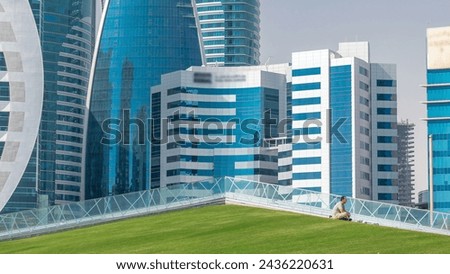 The high-rise district of Doha timelapse, seen from the Hotel Park, with green lawn and artificial hill in the foreground. Skyscrapers and palms