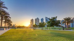 O Bairro Arranha-céus De Doha Timelapse Ao Pôr Do Sol, Visto A Partir Do Hotel Park, Com Gramado Verde E Colina Artificial Em Primeiro Plano. Arranha-céus E Palmeiras