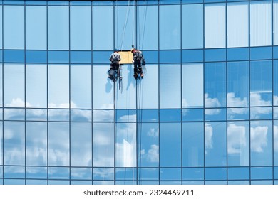 High-rise fitters repairing a glass panel in a window of a high-rise building.
