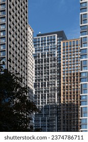 High-rise rectangular paired towers , lined with dark and light panels . Residential building against the blue sky . Modern architecture .