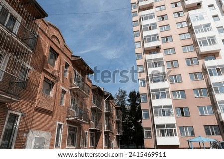 The façade of a high-rise residential building with partially glazed balconies in the city center of Ulan Bato, the capital of Mongolia, Central Asia and a multi-storey brick building