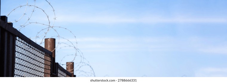 High-security prison area with barbed wire fencing and restricted access, symbolizing confinement, law enforcement, controlled environment, and strict protection of a secure facility.