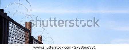 High-security prison area with barbed wire fencing and restricted access, symbolizing confinement, law enforcement, controlled environment, and strict protection of a secure facility.