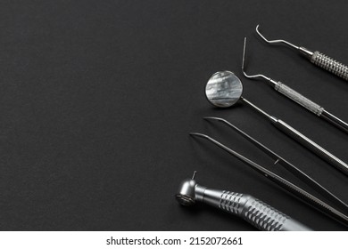 High-speed dental handpiece with bur, tweezers, a mouth mirror, a plugger and a curette on the black background. Medical tools.