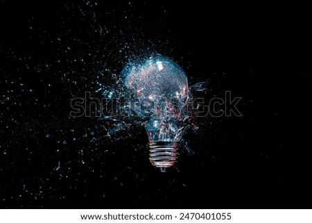 High-speed lightbulb exploding  glass shattering black background