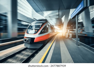 High-speed orange passenger train moving at railway station platform at sunset. Train station. Modern railway transportation concept with blurred motion effect. Railroad. Commercial transport - Powered by Shutterstock