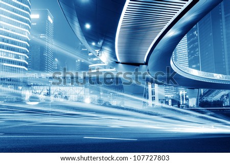 High-speed vehicles bright light trails on urban roads under the overpass at night