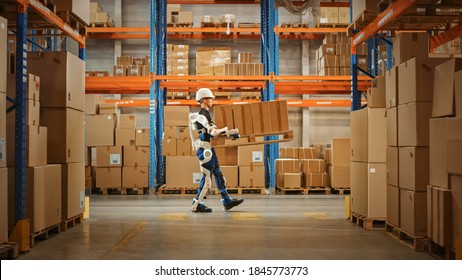 High-Tech Futuristic Warehouse: Manager Scans Packages for Inventory, Delivery in the Background Worker Wearing Advanced Full Body Powered exoskeleton, Walks with Heavy Pallet full of Cardboard Boxes - Powered by Shutterstock