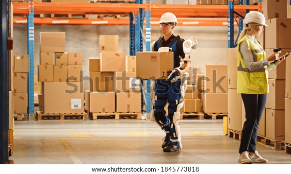 High-Tech Futuristic Warehouse: Worker Wearing\
Advanced Full Body Powered exoskeleton, Walks with Heavy Cardboard\
Box. Exosuit amplifies Human Performance, strength, Eliminates\
Work-Related Injuries