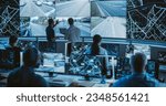 High-Tech International Logistics Office with Multiethnic Specialists Using Satellite Technology to Track a Fleet of Delivery Vehicles on a City Map. Large Display Shows Real-Time CCTV Feed and Report