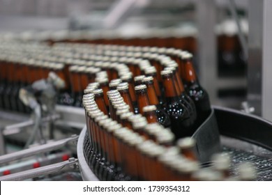 High-tech Line At The Plant For The Production Of Low Alcohol Drinks. On The Conveyor Are Glass, Brown Beer Bottles With Tin Lids. Motion, Art Blur Bokeh