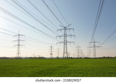 A lot of high-voltage power line, transmission tower overhead line masts, high voltage pylons also known as power pylons on the fields with grain.