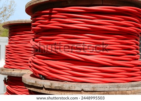High-voltage red electrical cable reels that can carry up to 30000 volts to connect electrical substations in the city