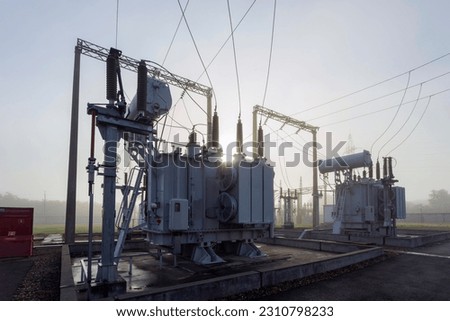 A high-voltage transformer illuminated in the fog by the sun.
Industrial substation in the fog in spring.
