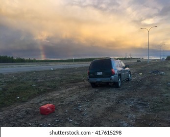 HIGHWAY 63, SOUTH OF FORT MCMURRAY, ALBERTA, CANADA - MAY 8, 2016: Abandoned Vehicles Left After Running Out Of Gas While Fleeing The Wildfire. Rainbow Shows Much Needed Precipitation.