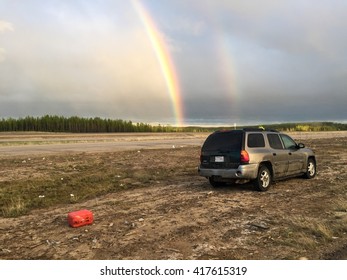 HIGHWAY 63, SOUTH OF FORT MCMURRAY, ALBERTA, CANADA - MAY 8, 2016: Abandoned Vehicle Left After Running Out Of Gas While Fleeing The Wildfire. Rainbow Shows Much Needed Precipitation.