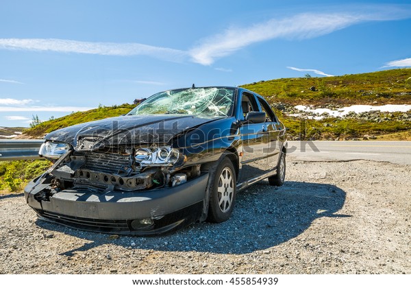 highway 7, Norway, Europe - June 15, 2014: a\
badly damaged car parked on a bend of the road after an incident\
the day before.