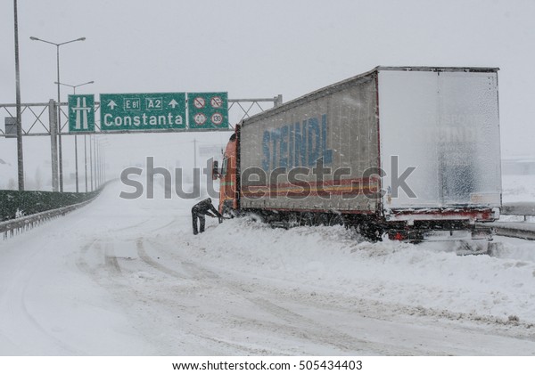 Highway A2, Romania, 17 January 2016: A truck\
driver shovels snow to free his truck on the closed highway A2, the\
main commercial route which connects Bucharest to the Black Sea\'s\
port, Constanta.