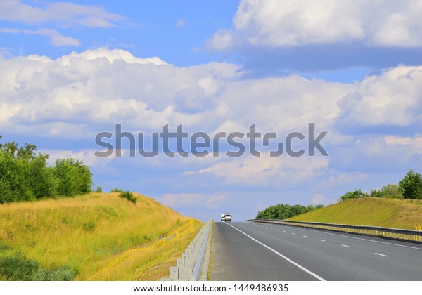 The highway among the hilly landscape of the\
steppe. Two white vans in the back burner. Beautiful road\
background. Free place.\
\
