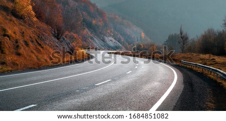 Highway in autumn mountains. Transportation background. New winding free road.