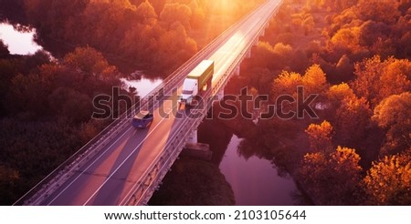The highway, the bridge over the river on which cars move. Dawn over the autumn forest. Wonderful landscape.