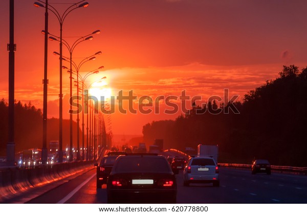 Highway with cars and street lamps\
along against  bright sunset background. Moscow,\
Russia.\
