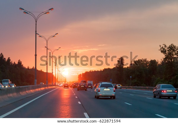 Highway with cars and street lamps\
along against  bright sunset background. Moscow,\
Russia.\
