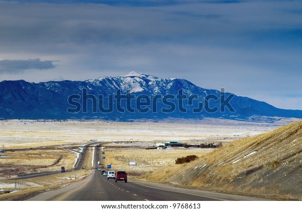 A highway in Colorado seems to lead to the Rocky\
Mountains ahead