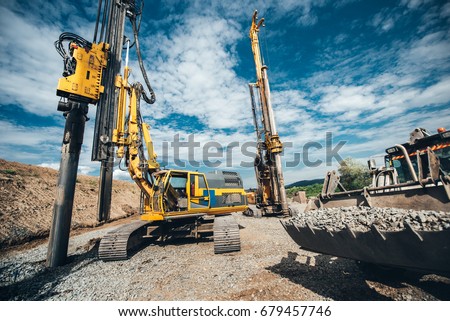 Highway construction site with heavy duty machinery. Two Rotary drills, bulldozer and excavator working 