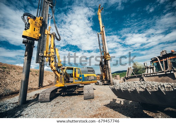 Highway construction\
site with heavy duty machinery. Two Rotary drills, bulldozer and\
excavator working 