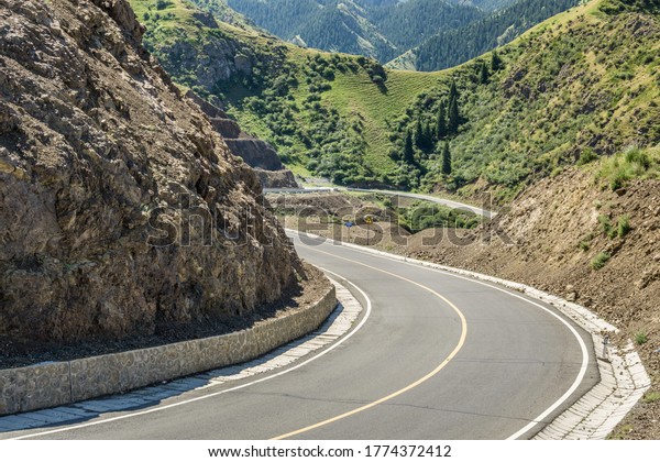 Highway curves in the background of\
mountains and grasslands in Xinjiang, China in\
summer