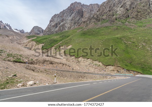Highway curves in the background of\
mountains and grasslands in Xinjiang, China in\
summer