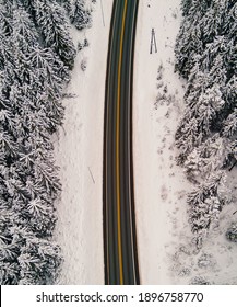 Highway Cutting Through A Snow Covered Forest Landscape In The Midst Of Winter.