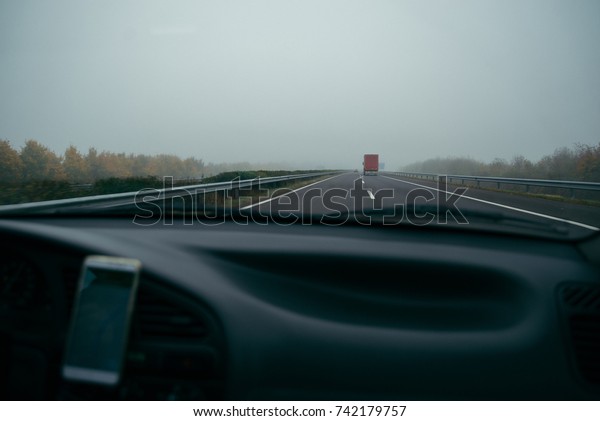 highway in fog view from car with phone that\
showing navigation