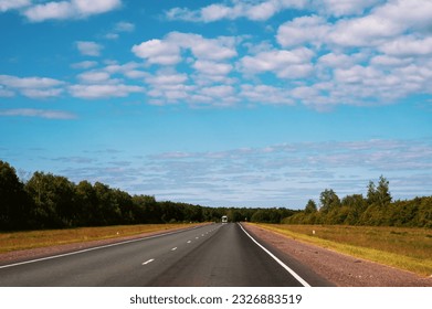 highway going into the distance. Gorgeous view of highway going into distance through forests against background of blue sky with white clouds.