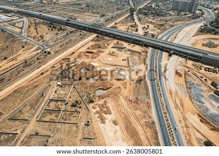 Highway interchange construction in India with elevated roads and earthmoving machinery shows urban infrastructure growth and modern transportation development.