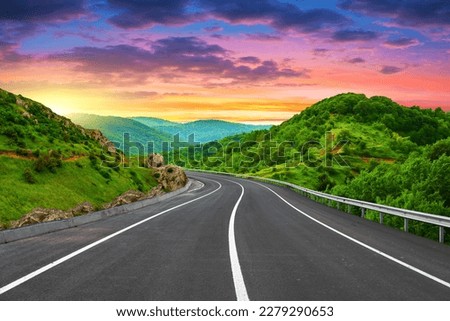 Highway landscape at colorful sunset in summer. Mountain road landscape at dusk. Beautiful nature scenery in green mountains. Travel landscape for summer vacation on highway. Bavaria, Germany.