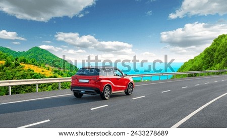 Highway landscape on coast on way to summer holiday. Red car drive on the road of mediterranean beach. Vacation travel trip on asphalt road with nature scenery among green mountains in the sea.